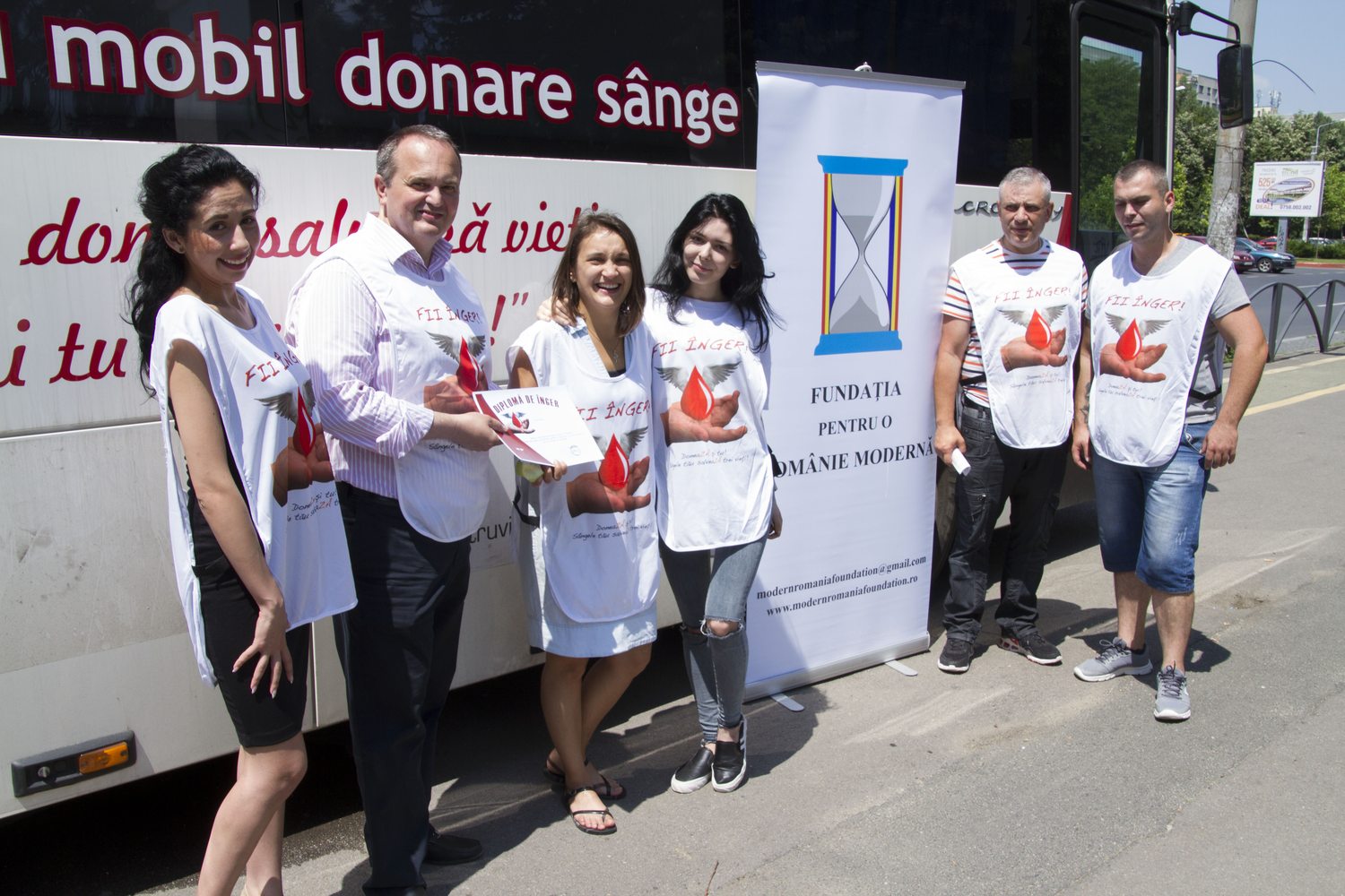 Voluntari FPRM lângă autocarul mobil de donare de sânge și roll-up-ul Fundației